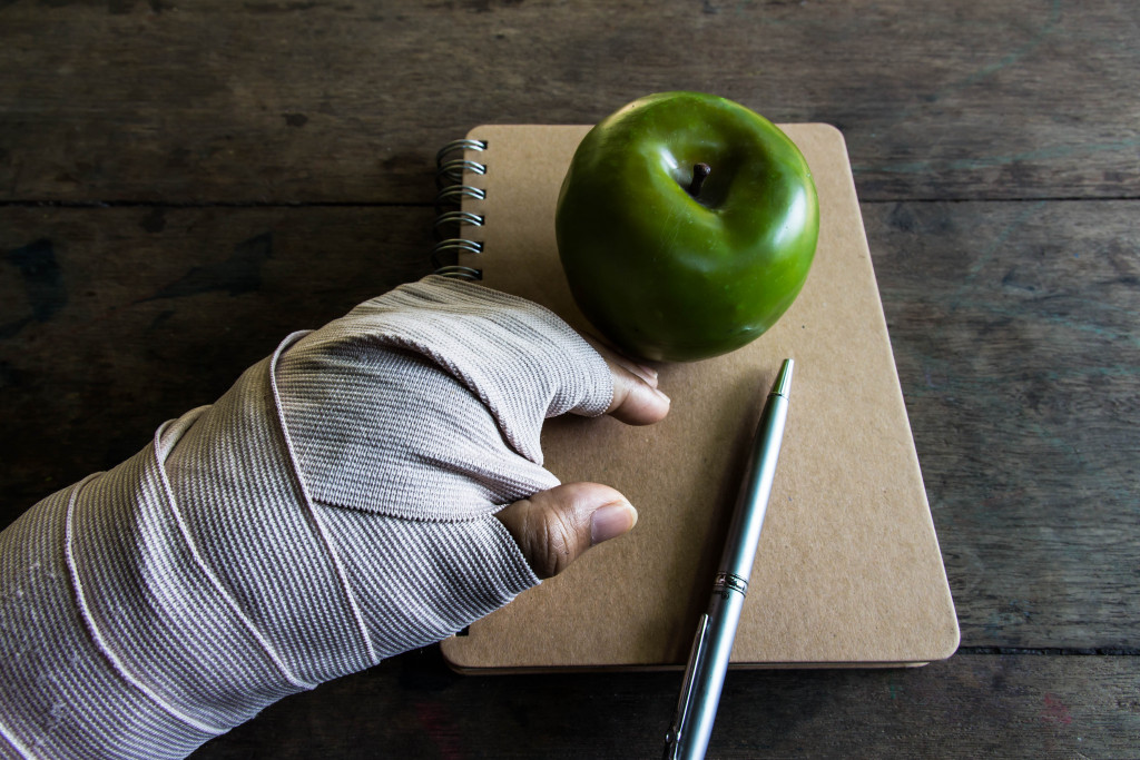 bandaged hand reaching for a green apple