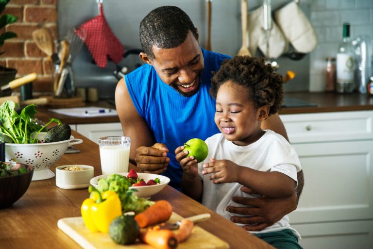 A dad teaching her daughter to eat fruits