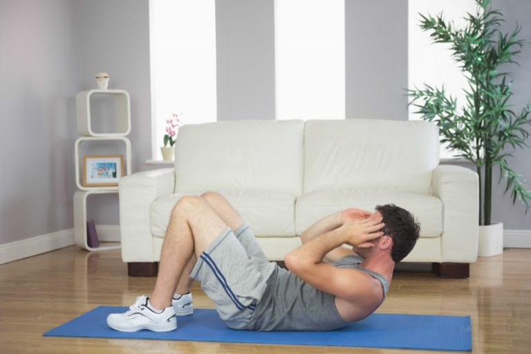 sporty man doing sit ups in bright living room